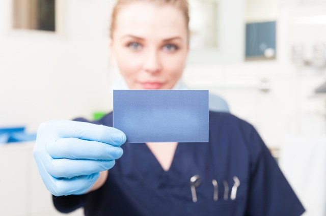 Closeup of business card hold by female dentist with copyspace